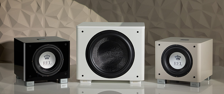 An image containing three REL subwoofers from left to right in gloss black, gloss white and grey.