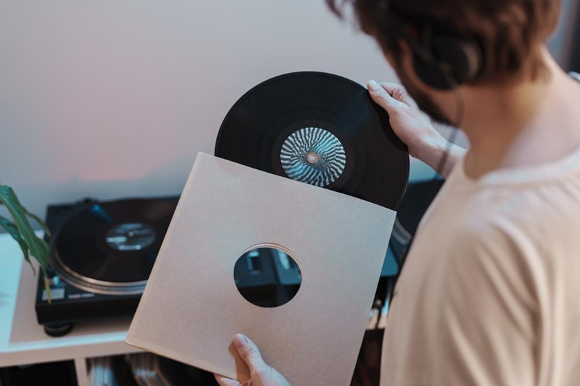 An image depicting a person taking a vinyl record out of a paper sleeve.