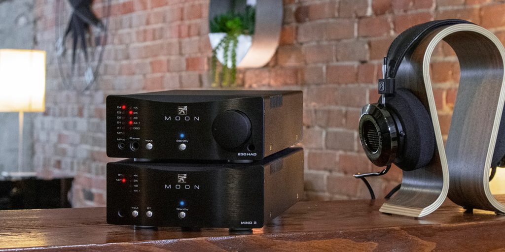 An image of the Moon MiND 2 streamer with a headphone amp sitting on top of it and a pair of headphones to the right.